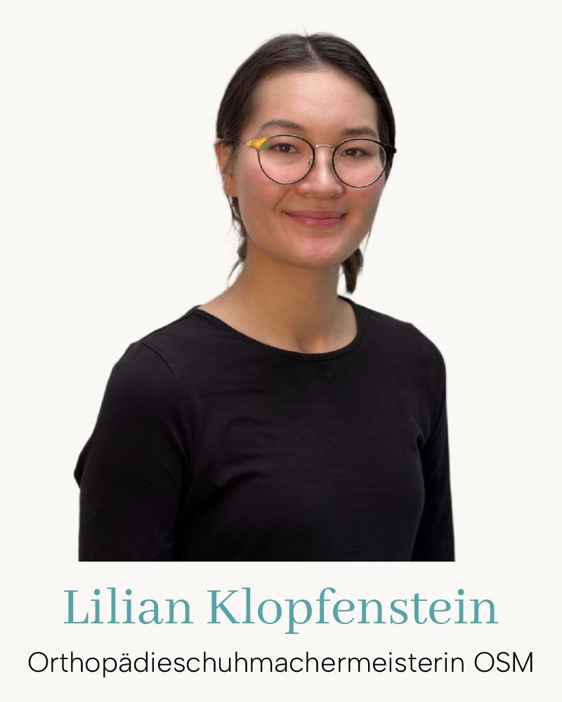 Porträt einer Orthopädieschuhmachermeisterin (OSM) mit Brille im schwarzen Shirt vor hellem Hintergrund