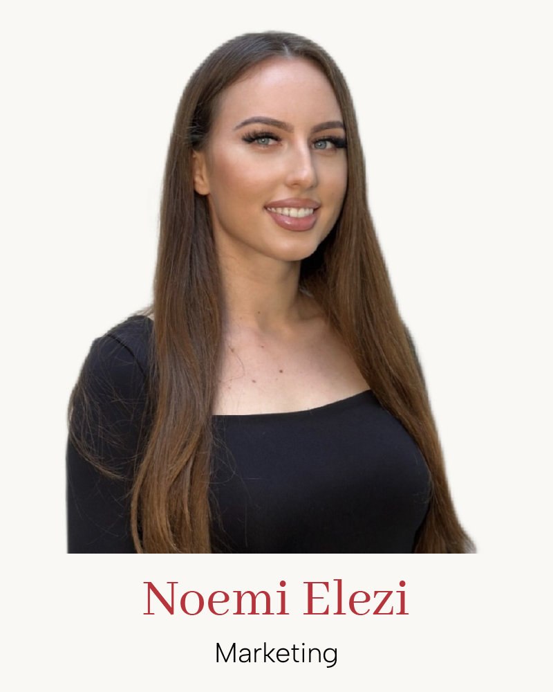 Business-Porträt einer Marketing-Expertin, lächelnd mit langen braunen Haaren vor hellem, neutralem Hintergrund.