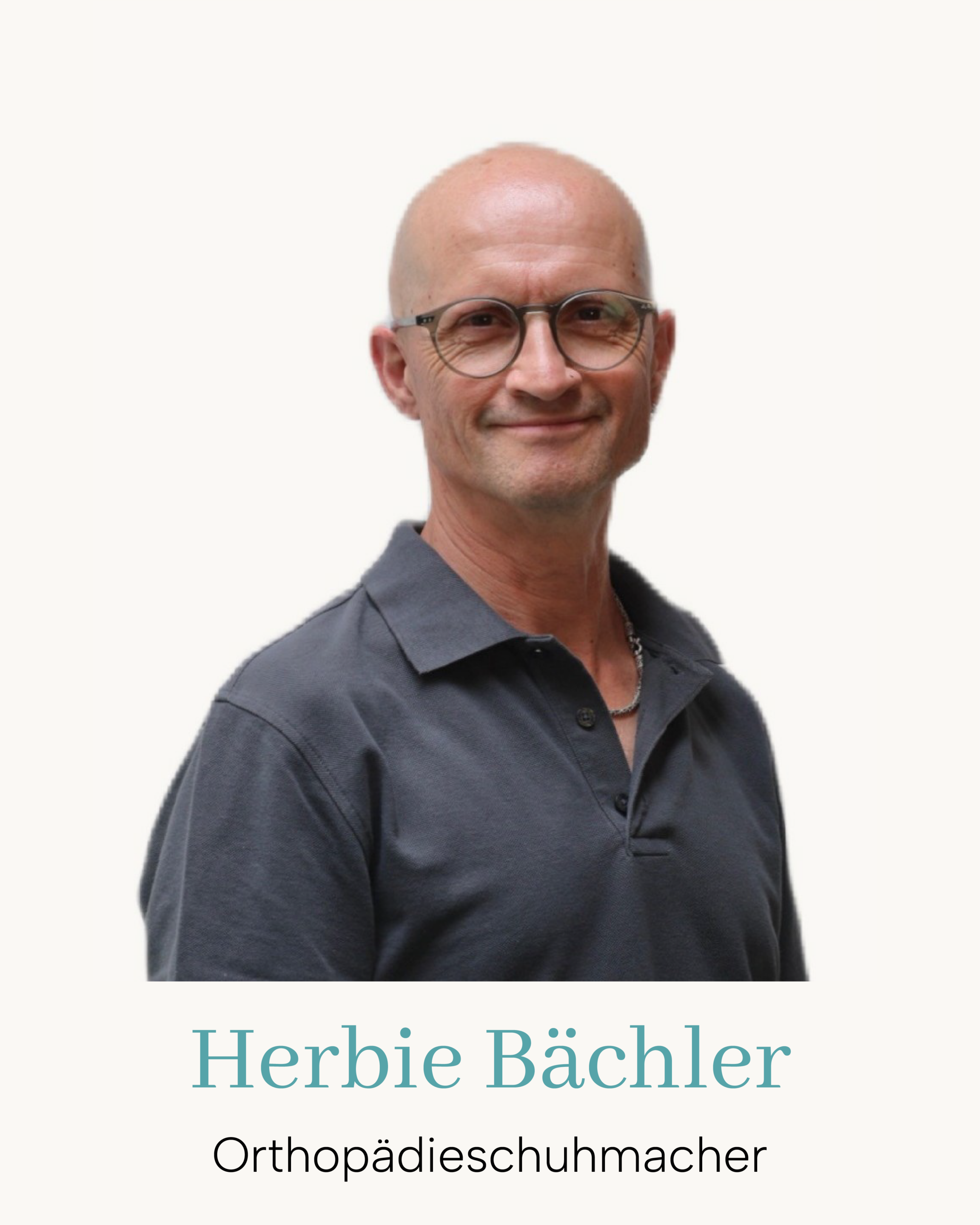 Porträt eines lächelnden Orthopädieschuhmachers mit Brille im grauen Polohemd vor hellem Hintergrund.